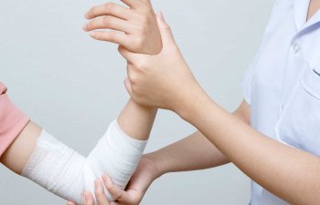 Nurse applying bandage to patient injured elbow.